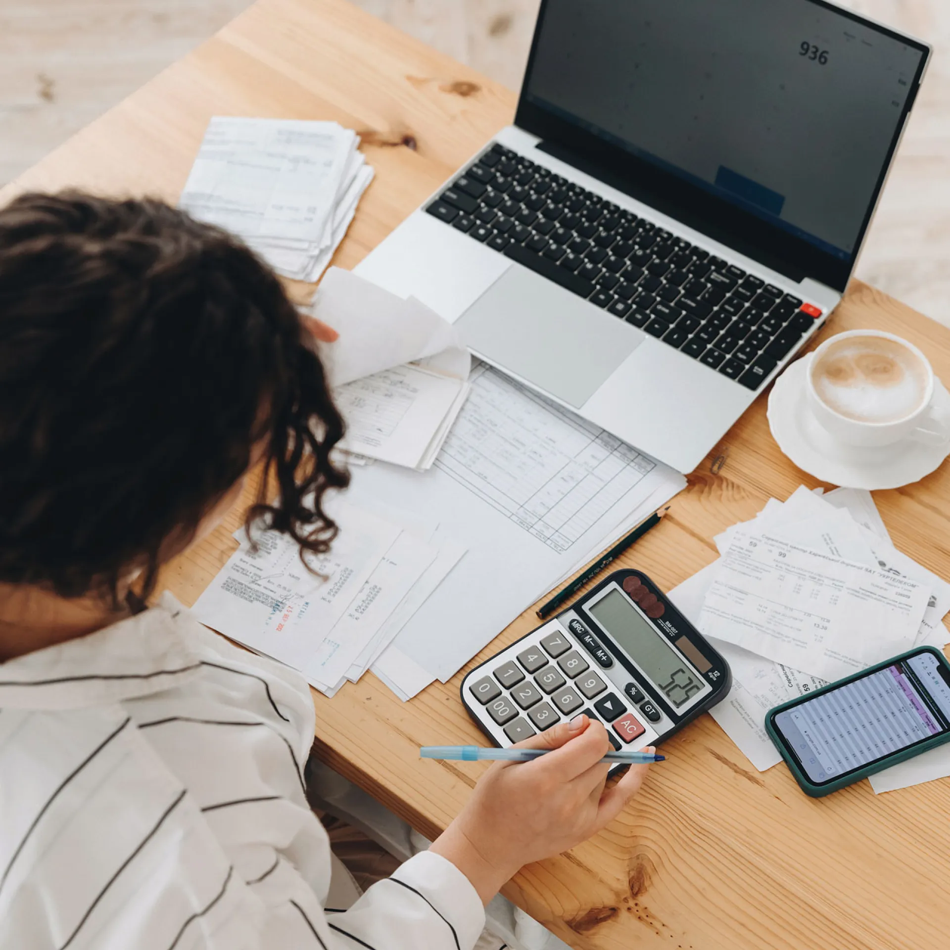 Bovenaanzicht van een vrouw die thuis in de keuken werkt met financiële papieren
